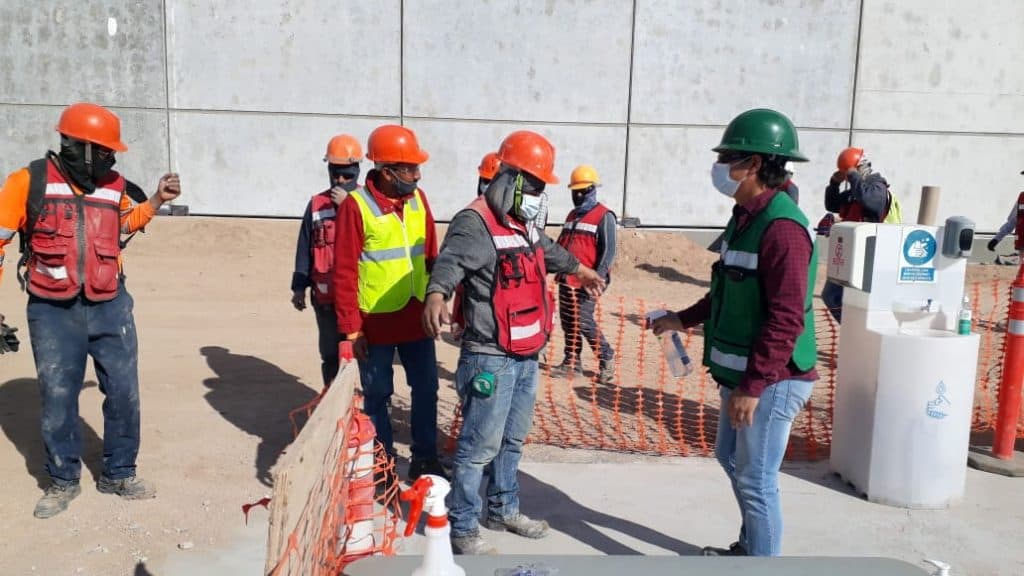 Workers lining up to do the hygiene protocol before entering to the construction area.