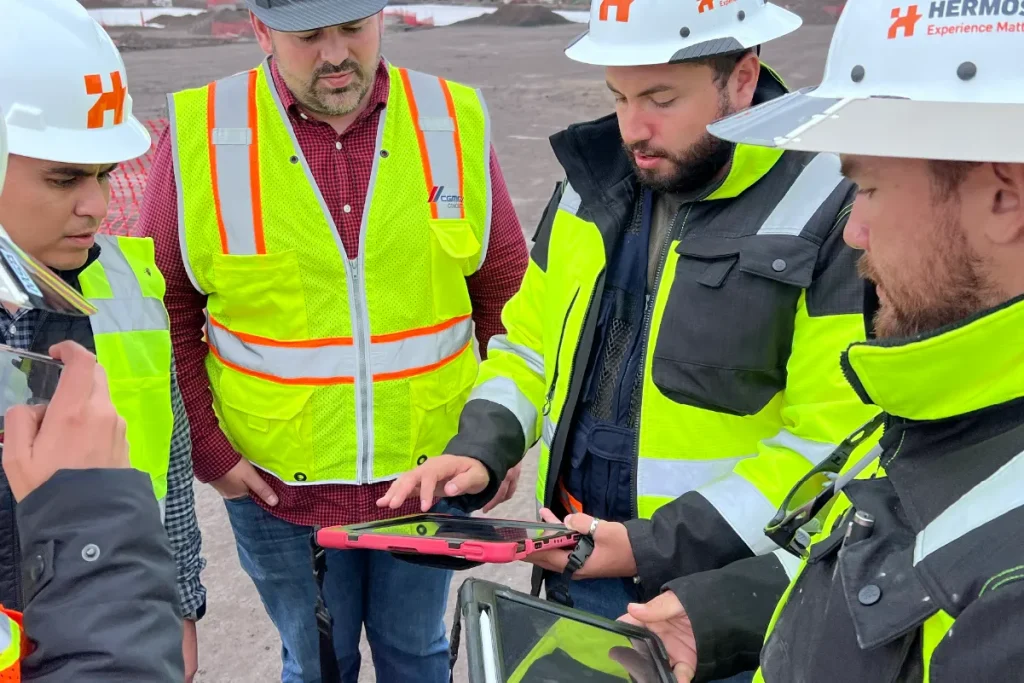 Equipo de trabajo en sitio de construccion usando tablet con diseños digitales